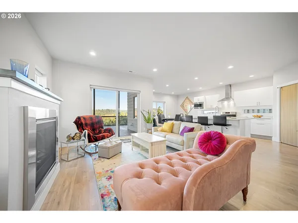 a living room with furniture kitchen view and a wooden floor