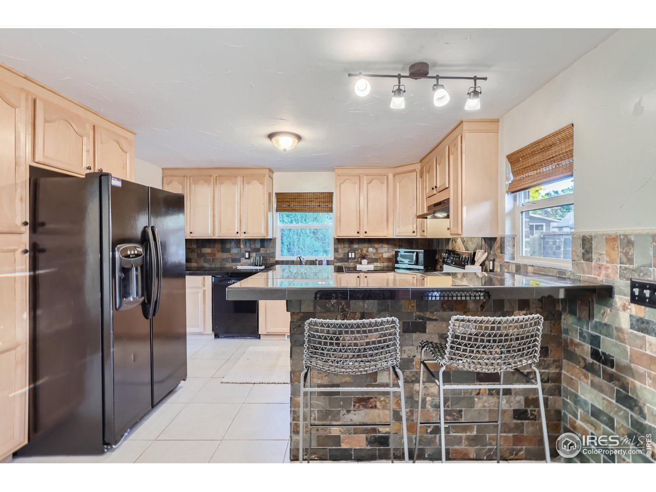 25 Reed Place Longmont, CO 80504 - Photo 6 of 30 a kitchen with stainless steel appliances granite countertop a refrigerator a sink a stove a dining table and chairs
