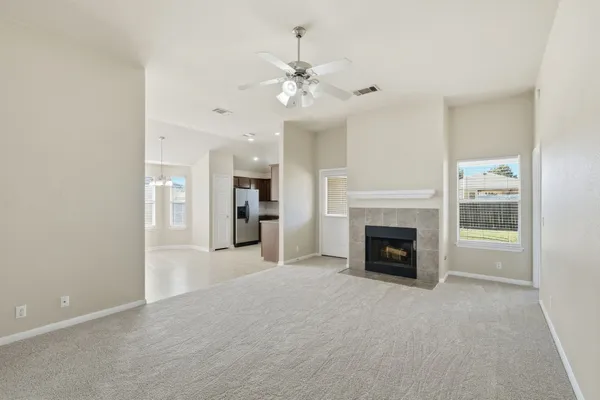 a view of a livingroom with a fireplace a ceiling fan and windows
