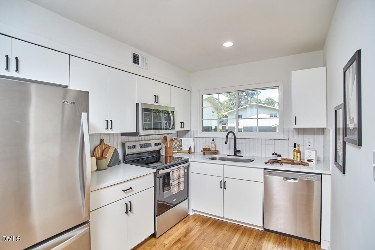 2613 McNeil Street, Unit E Raleigh, NC 27608 - Photo 12 of 28 a kitchen with stainless steel appliances a refrigerator sink and microwave