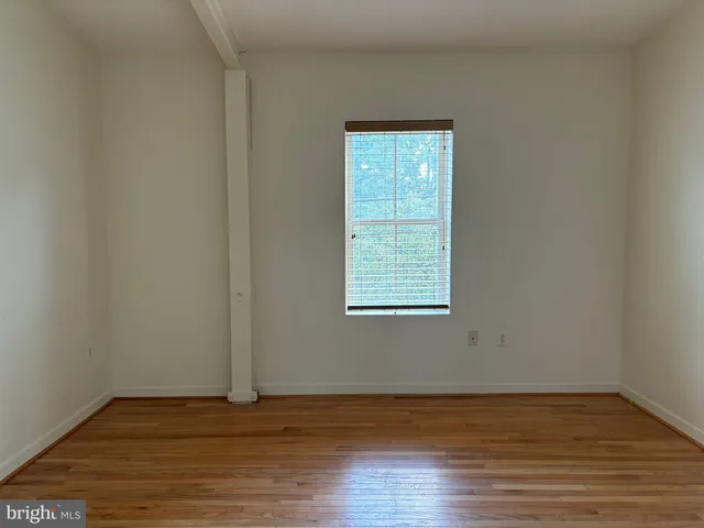 a view of an empty room with wooden floor and closet