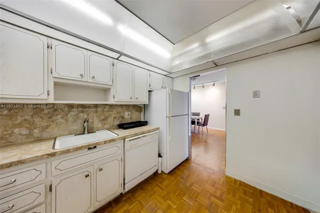 a kitchen with white cabinets and sink