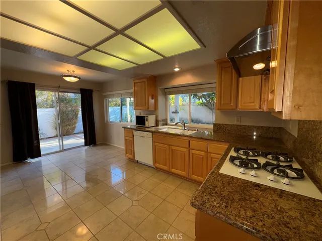 a kitchen with stainless steel appliances granite countertop a stove a sink dishwasher and a refrigerator with wooden cabinets