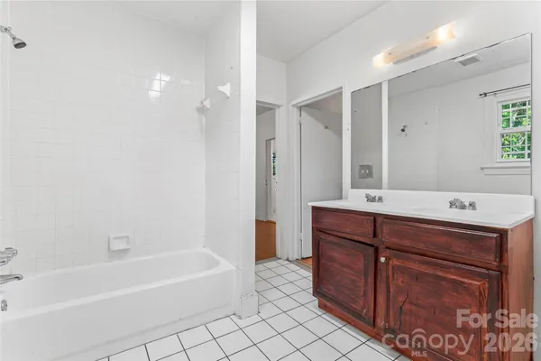 a bathroom with a tub sink vanity granite and shower