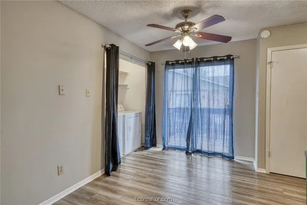 an empty room with wooden floor chandelier fan and windows