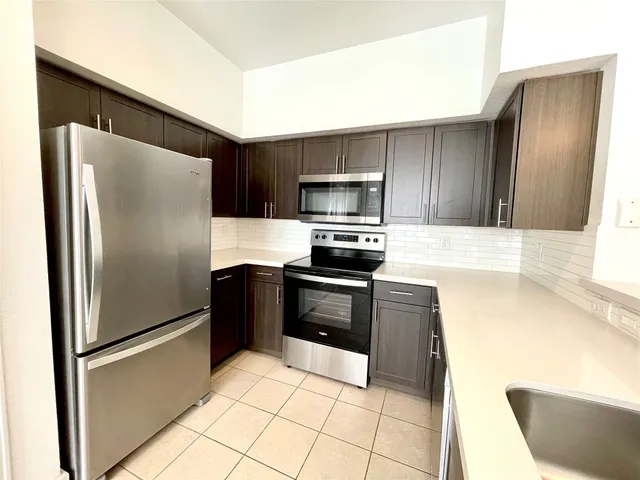 a kitchen with granite countertop a refrigerator and a sink