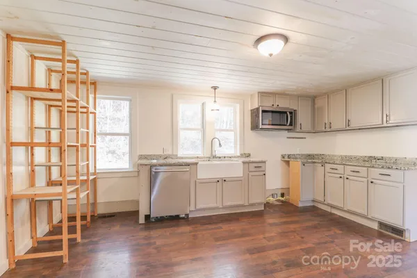 a large kitchen with stainless steel appliances granite countertop a stove a sink and white cabinets with wooden floor