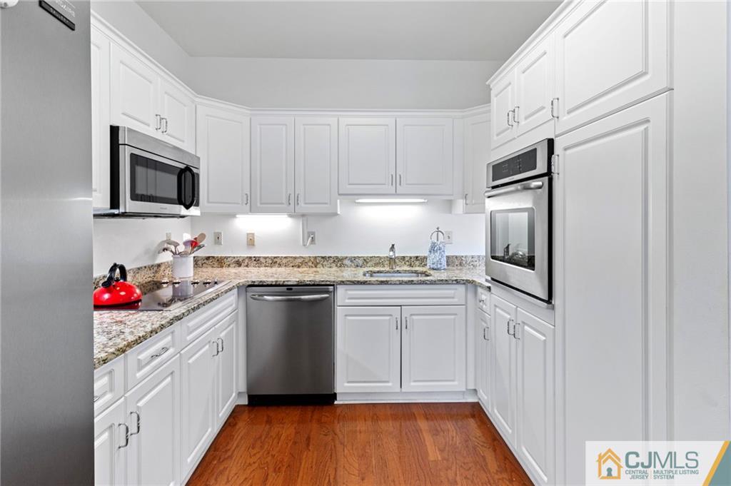 2126 Windrow Drive Plainsboro, NJ 08540 - Photo 8 of 32 a kitchen with stainless steel appliances granite countertop a stove top oven a refrigerator and white cabinets with wooden floor