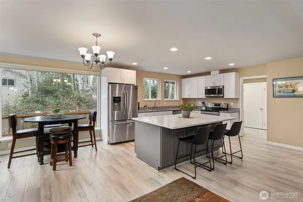 a open kitchen with stainless steel appliances kitchen island granite countertop a table chairs sink and cabinets