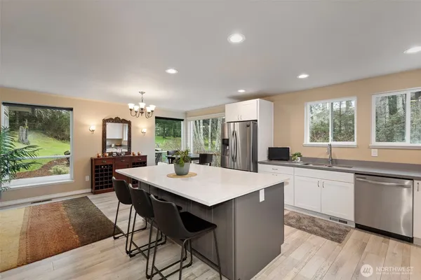 a large kitchen with kitchen island a dining table chairs and a refrigerator