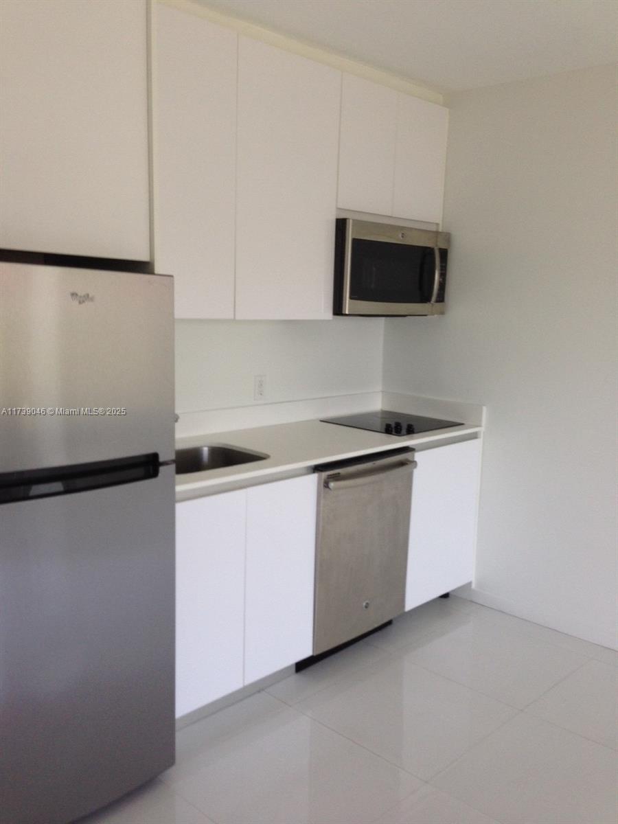 801 15th Street, Unit 109 Miami Beach, FL 33139 - Photo 5 of 9 a kitchen with stainless steel appliances a refrigerator sink and white cabinets