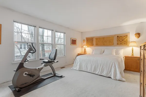 a bedroom with a bed a table and large windows