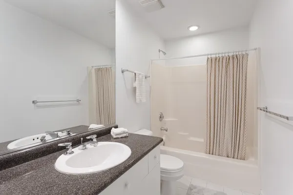 a bathroom with a granite countertop sink a toilet a mirror and shower