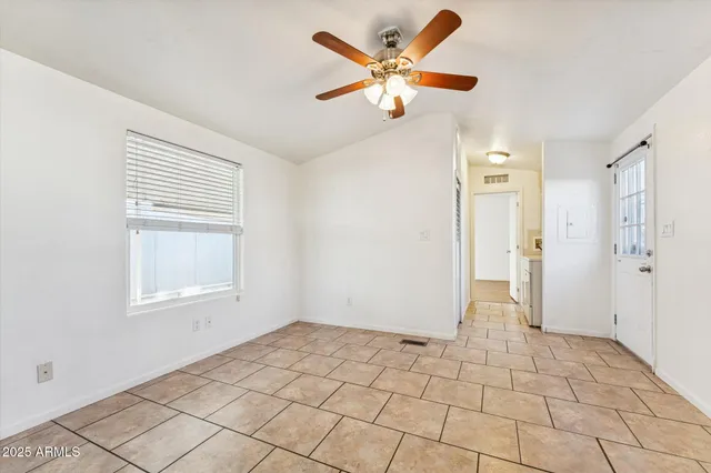 an empty room with a ceiling fan and window