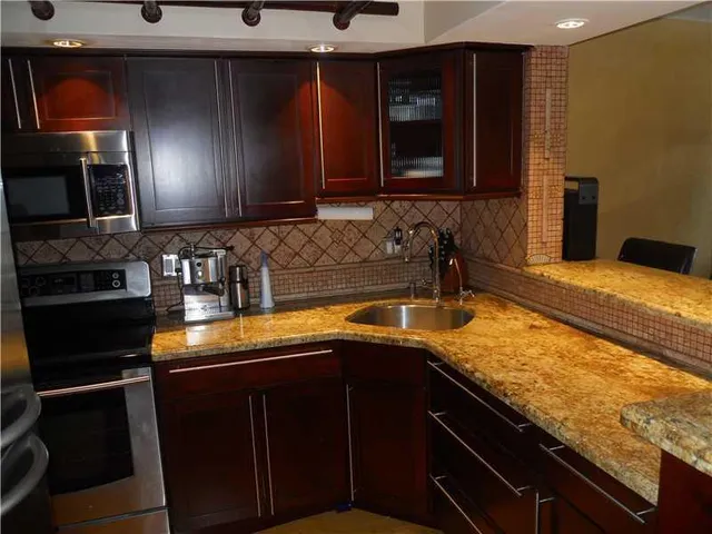 a kitchen with granite countertop a sink a stove and refrigerator