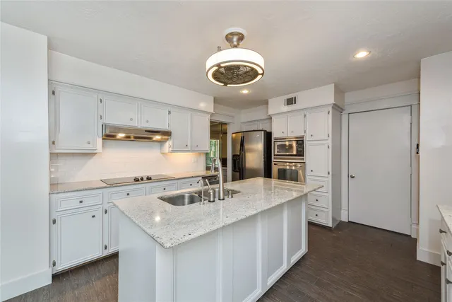 a kitchen with stainless steel appliances granite countertop a sink a stove and a refrigerator