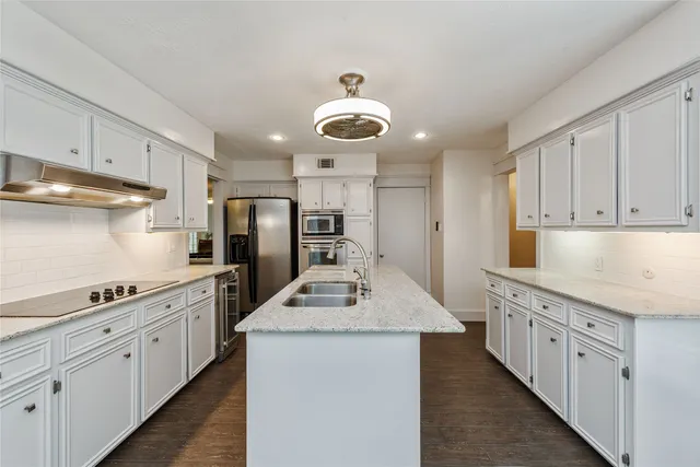 a kitchen with stainless steel appliances granite countertop a sink stove oven and white cabinets