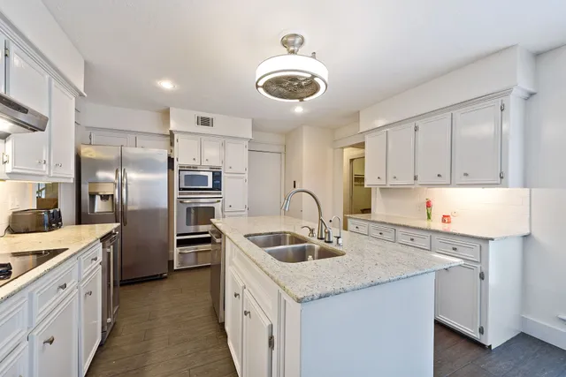 a kitchen with stainless steel appliances granite countertop a sink stove and refrigerator