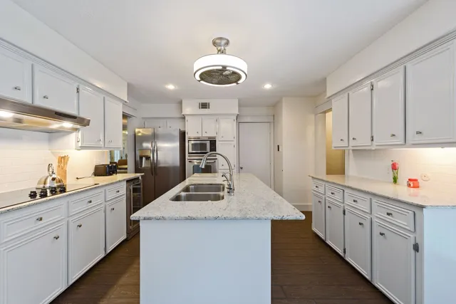 a kitchen with stainless steel appliances kitchen island granite countertop a sink a stove counter space and cabinets