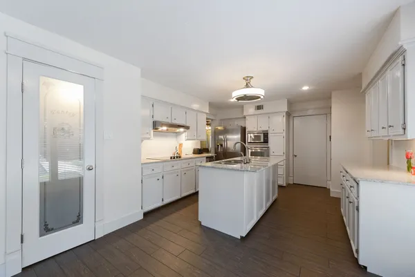 a kitchen with white cabinets a sink dishwasher and a stove with wooden floor