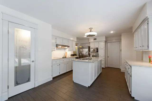 a kitchen with white cabinets a sink dishwasher and a stove with wooden floor