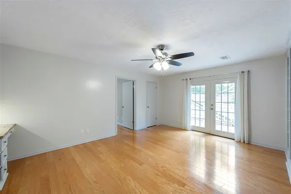 a view of an empty room with chandelier and wooden floor