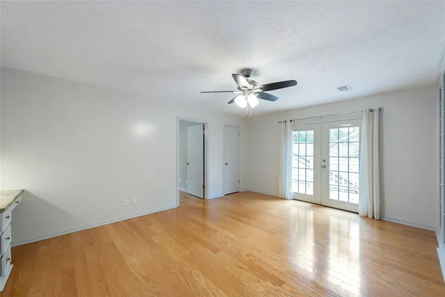 a view of an empty room with chandelier and wooden floor