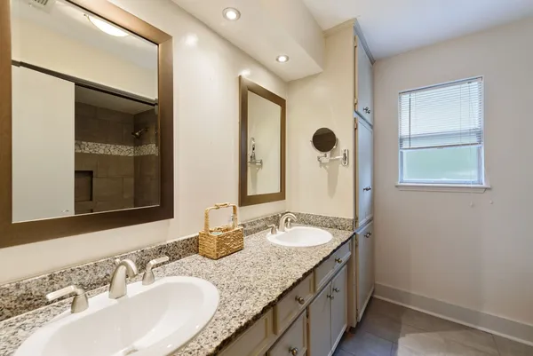 a bathroom with a granite countertop sink a mirror and a shower