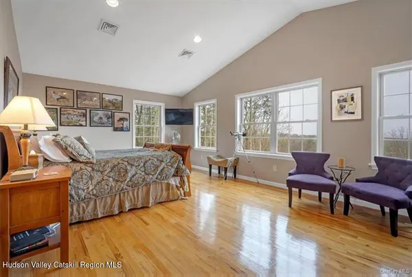 a bedroom with a bed a couch and dresser with wooden floor