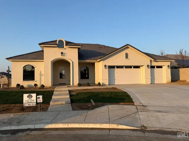 a view of a white house with a yard and parking space