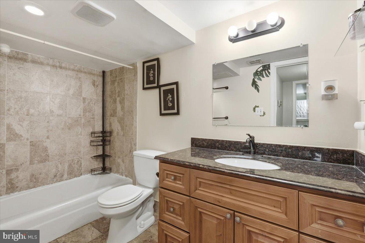 8459 Greenbelt Road, Unit T1 Greenbelt, MD 20770 - Photo 18 of 27 a bathroom with a granite countertop sink toilet and painting on the wall