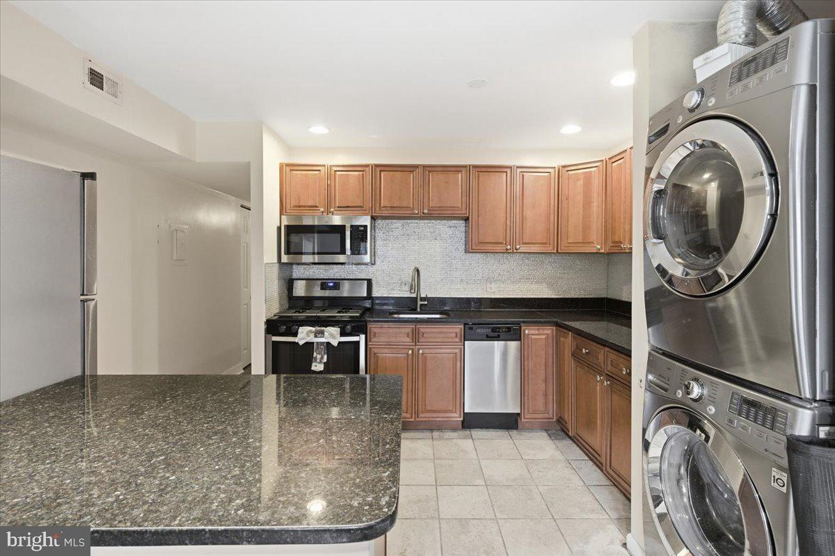8459 Greenbelt Road, Unit T1 Greenbelt, MD 20770 - Photo 5 of 27 a kitchen with stainless steel appliances granite countertop a sink a stove a washer and dryer