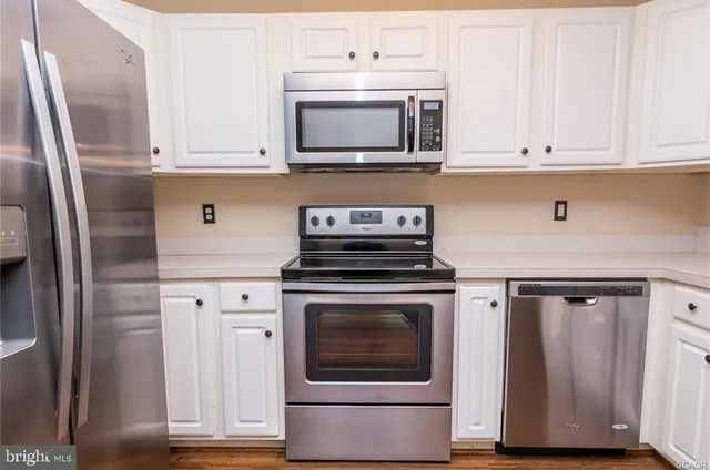 a kitchen with granite countertop white cabinets and stainless steel appliances