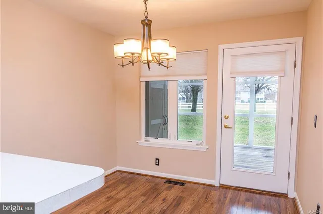 a view of a room with wooden floor chandelier and windows