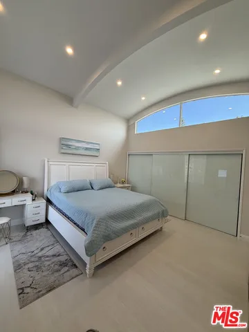 a spacious bedroom with a bed and painting on the wall