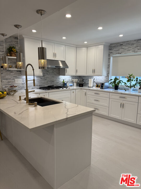 13218 Fiji Way, Unit J Marina del Rey, CA 90292 - Photo 10 of 33 a large kitchen with granite countertop a stove top oven a sink a counter space and cabinets