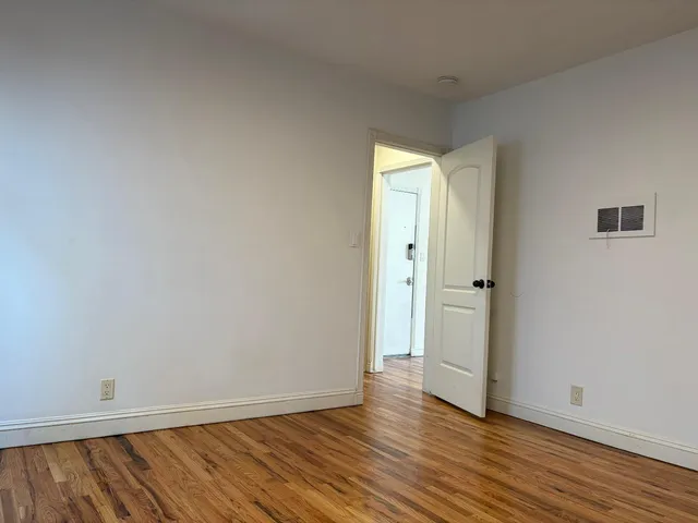 a view of an empty room with wooden floor and closet