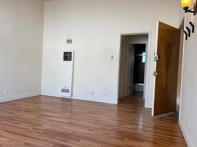 a view of an empty room with wooden floor and closet