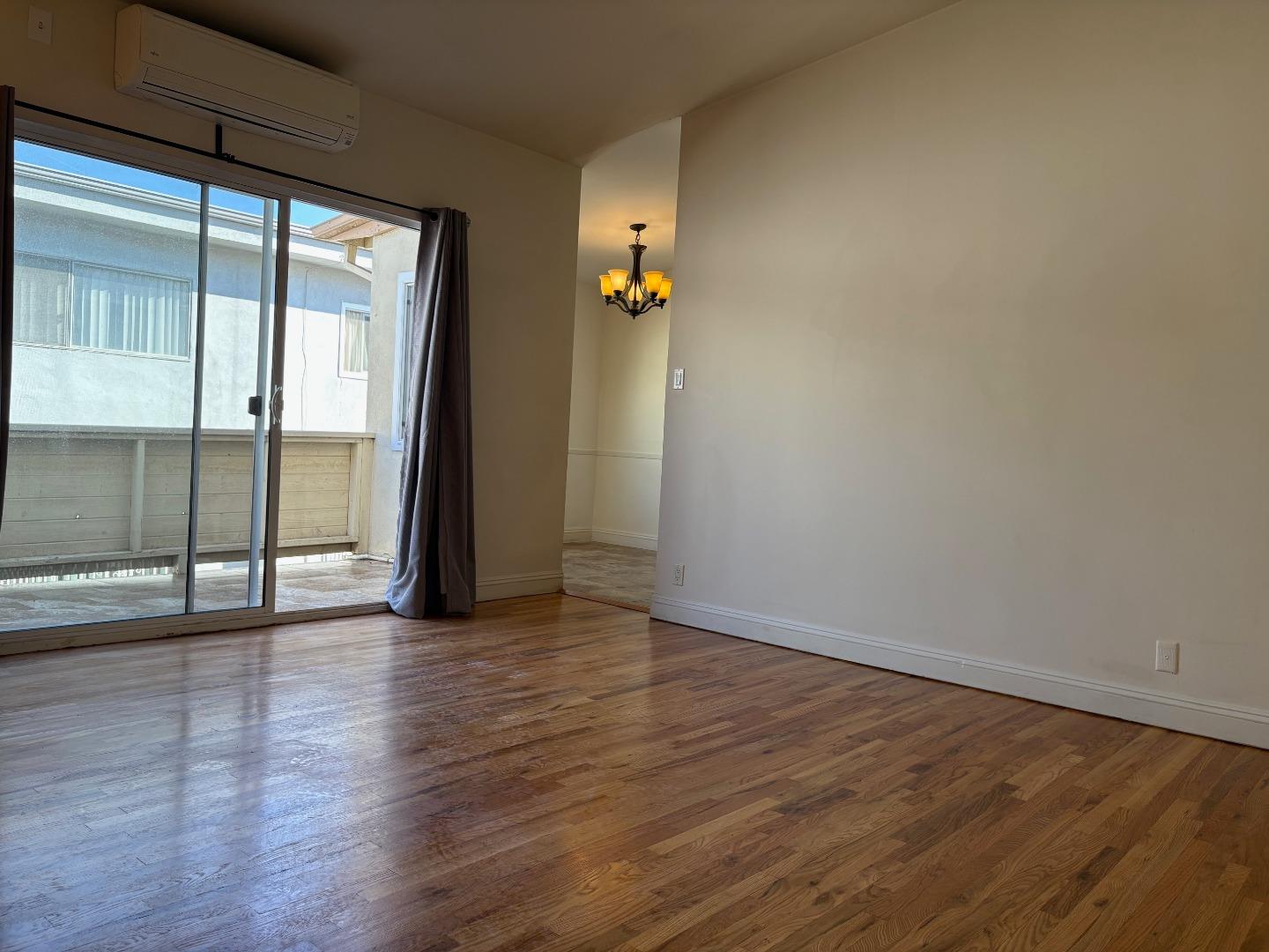 11719 Mayfield Avenue, Unit 6 Los Angeles, CA 90049 - Photo 7 of 20 an empty room with wooden floor and windows
