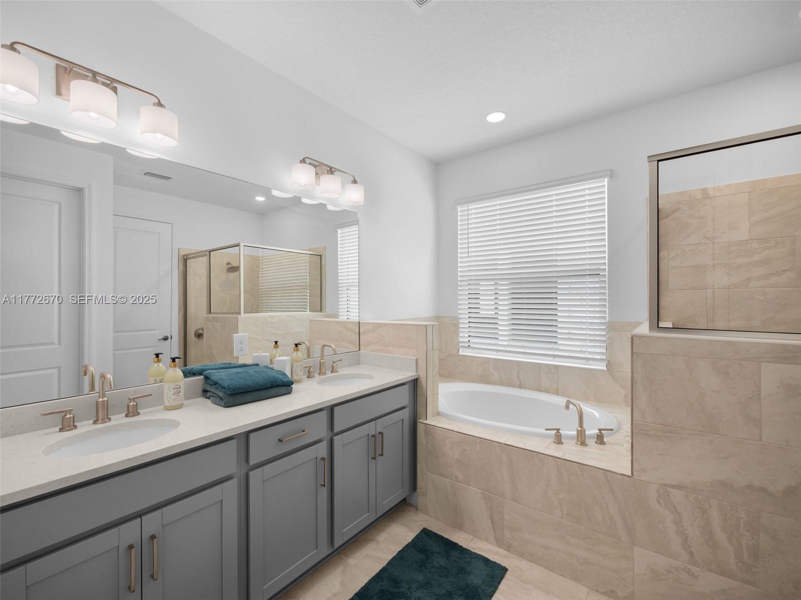 516 Ranch Oak Circle Port St. Lucie, FL 34984 - Photo 17 of 44 a bathroom with double vanity sinks a large mirror and a bathtub