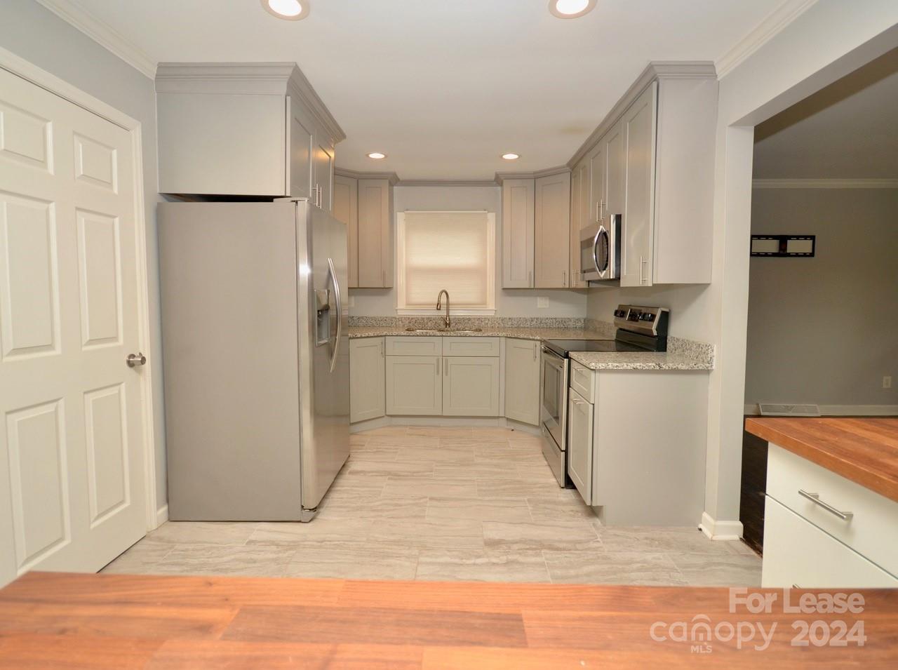 6334 Beecher Drive Charlotte, NC 28215 - Photo 9 of 27 a kitchen with stainless steel appliances granite countertop a refrigerator sink and white cabinets