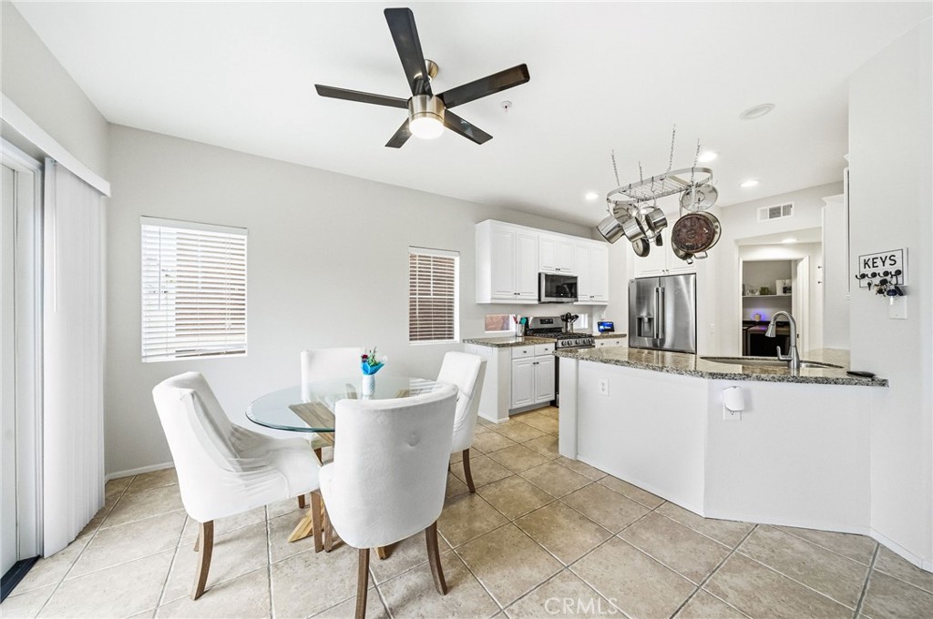 33656 Winston Way, Unit A Temecula, CA 92592 - Photo 5 of 46 a kitchen with stainless steel appliances kitchen island granite countertop a stove a sink a dining table and chairs with wooden floor