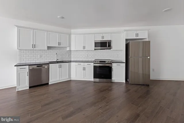 a kitchen with stainless steel appliances granite countertop a stove top oven a sink and white cabinets