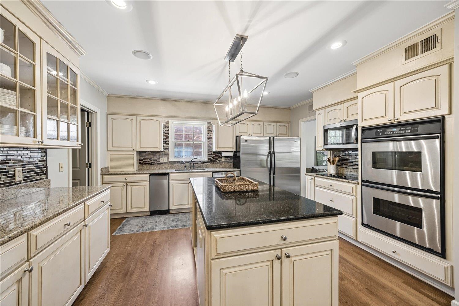 5311 South Angela Road Memphis, TN 38120 - Photo 15 of 40 a kitchen with stainless steel appliances granite countertop a refrigerator a stove and white cabinets with wooden floors