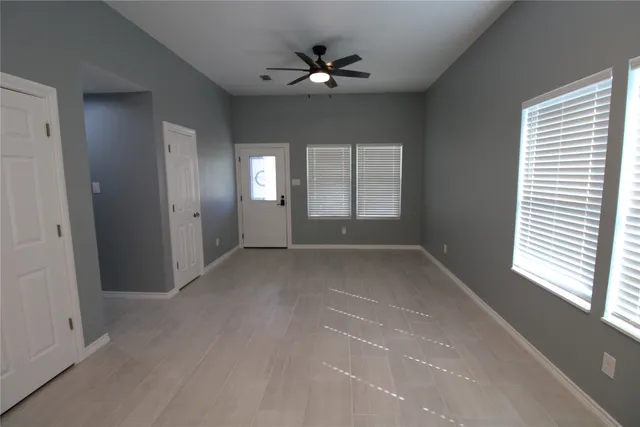 an empty room with windows and ceiling fan