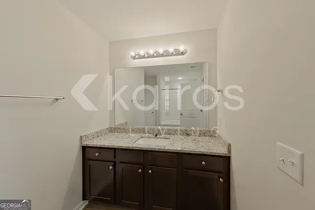 a bathroom with a granite countertop sink a mirror and a shower