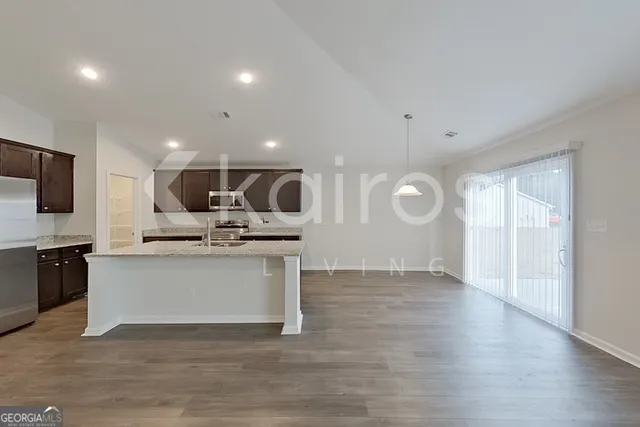 a kitchen with stainless steel appliances granite countertop a sink dishwasher a refrigerator and a microwave with wooden floor