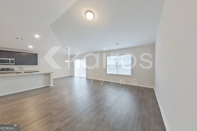 a view of kitchen and empty room with wooden floor