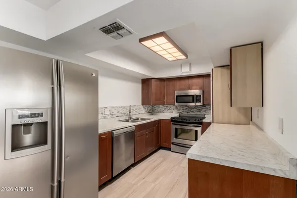 a kitchen with stainless steel appliances granite countertop a refrigerator oven a sink dishwasher and a refrigerator with wooden floor