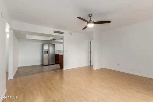 an empty room with wooden floor ceiling fan and windows